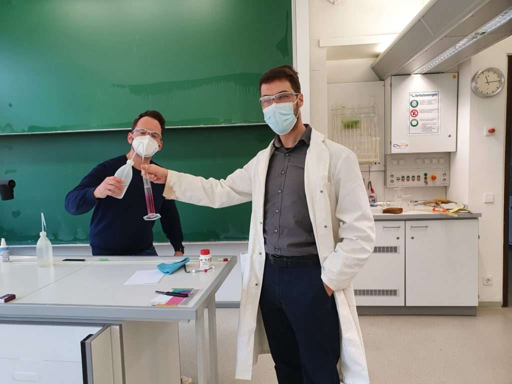 Ein Lehrer führt ein Experiment mit einem Schüler im Chemie Zimmer durch.