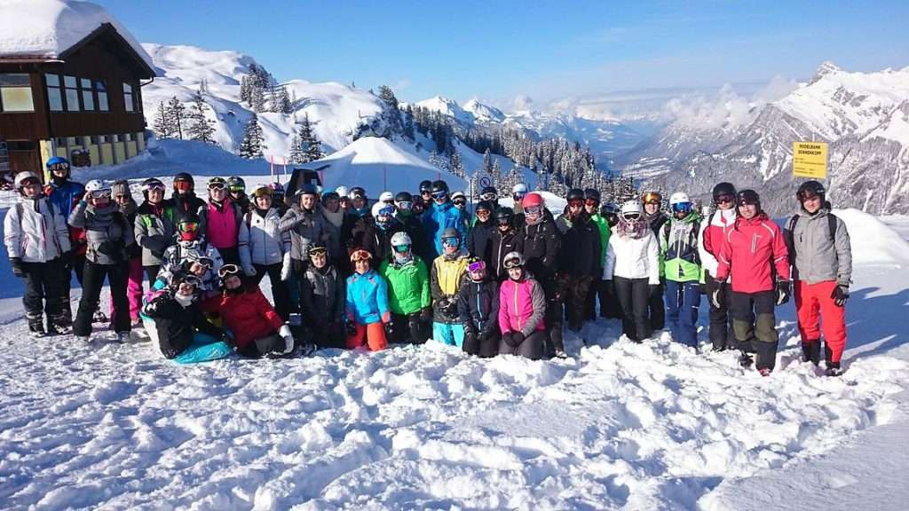 Schülerinnen und Schüler der Ski- und Snowboard AG stehen in einer großen Gruppe im Schnee im Skigebiet.