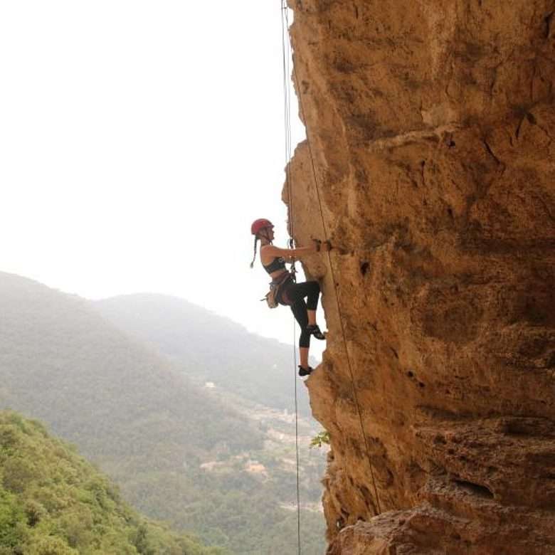 Eine Schülerin aus der Kletter AG klettert an einer Felswand hoch.